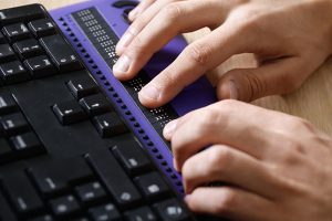 A purple and black refreshable braille display-keyboard.