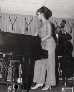 Nina Simon standing and playing the piano