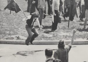 A May 4th protestor holding a flag jumps in the air