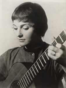 Judy Collins looking down at her guitar while she plays it