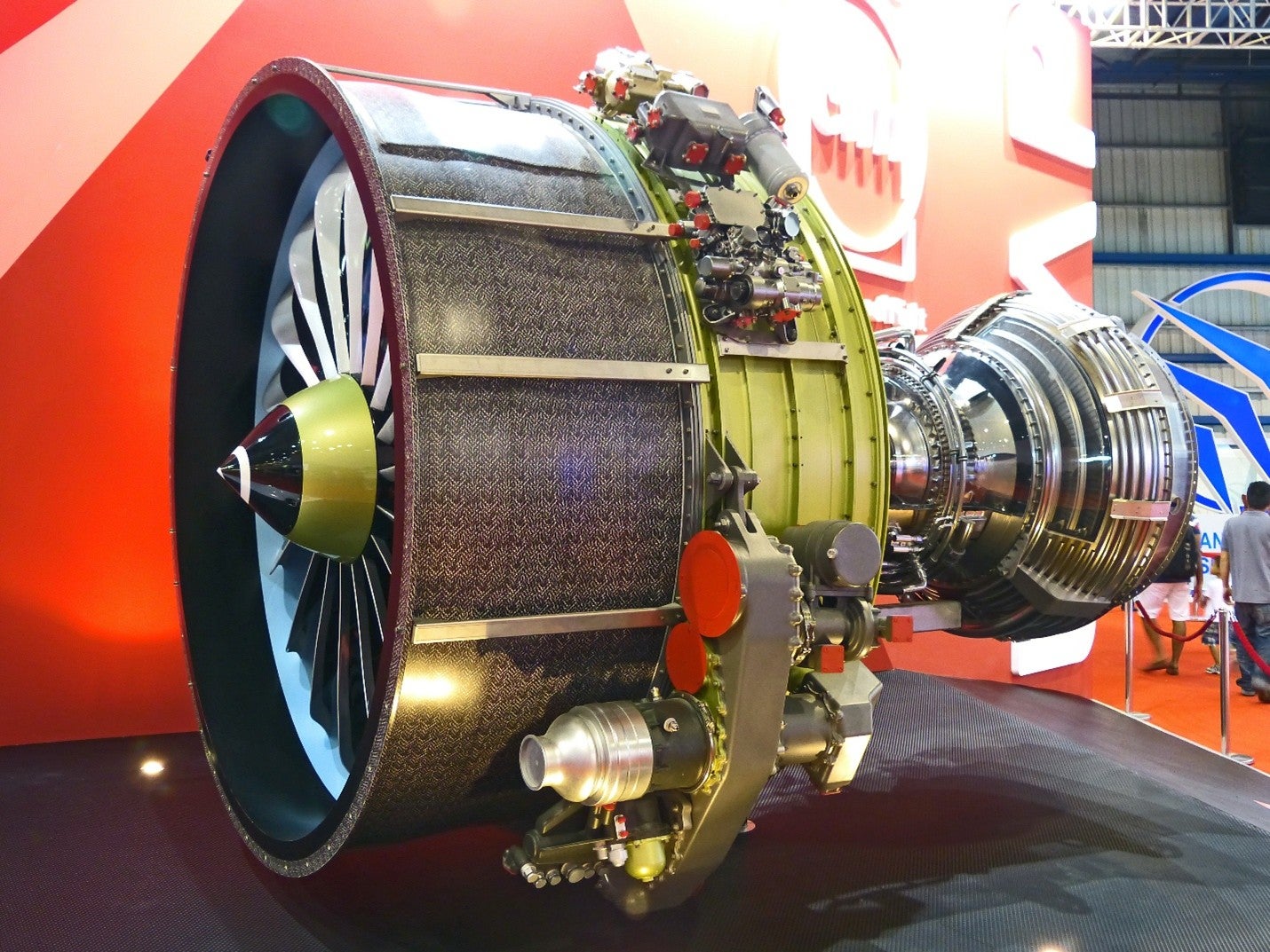 An engine of a jet displayed on a stage with a red background