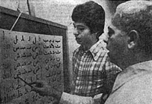 Dr. Emile N. Habiby uses this chart to teach the alphabet sounds of the Arabic language while his son, Najib looks on. (Cleveland Press, 8/17/77)
