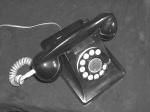 A picture of an old rotary phone that is in black and white.