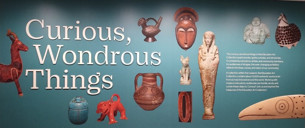 Wall in EAC gallery at Cleveland Museum of Art featuring objects the text "Curious Wondrous Things"