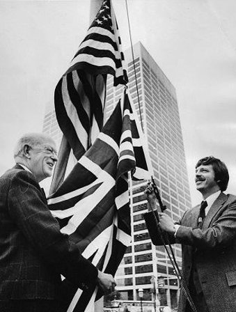 DOUBLE FLAG RAISING. In preparation for Cleveland’s first British royal visit, Press editor Tom Boardman raises the Stars and Stripes on The Press roof, whilst the author raises the British Union Flag under it. Hopefully Prince Charles will see both when he drives into the city from Burke Lakefront airport in a couple of hours.