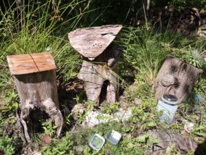 photo of a woodland garden with fairy village made out of logs. A silver tin is open in the foreground