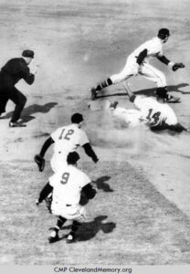 Larry Doby sliding into 2nd base as three Boston Braves infielders try to make a play; an umpire watches to make the call.