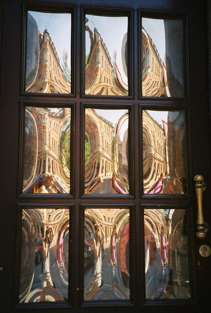 A nine pane window reflecting the building across the street at a different angle in each pane.