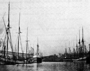 Whiskey Island -- River Boats unloading ore in 1880. In the background is St. Malachi Church on Whiskey Island (Plain Dealer).