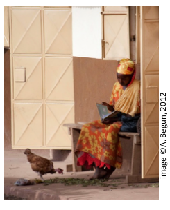person seated near a street with a chicken roaming around