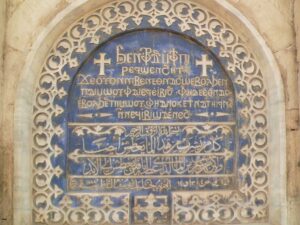 Image of a Coptic inscription of the Biblical verse on the top, Arabic on the bottom.